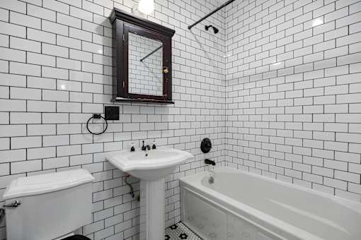 A white bathroom with a white tub, sink, and toilet.