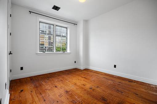 A room with a window and wooden floors.