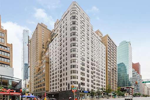 A tall building with a lot of windows in the middle of a city street.