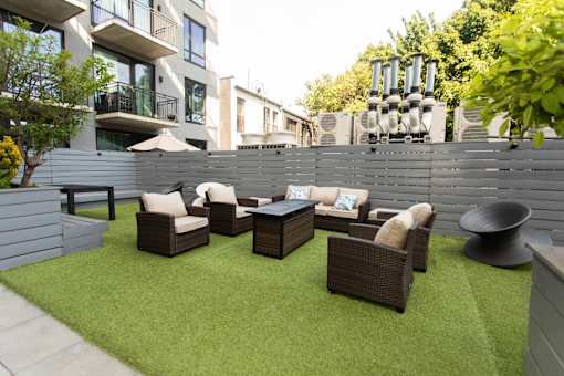 Outdoor patio lounge with artificial turf and wicker seating at 1134 Fulton Street Apartments, Brooklyn, New York