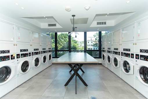 Modern communal laundry room with folding table at 1134 Fulton Street Apartments, New York