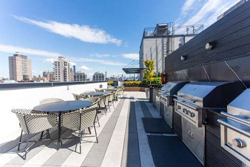 Rooftop terrace with grills and dining area at 260 Gold Apartments, New York