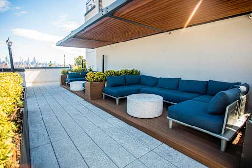 Rooftop lounge with blue sectional seating and skyline views at 260 Gold Apartments, Brooklyn, NY 11201