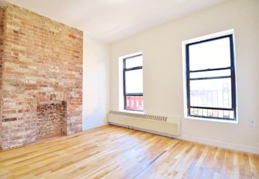 A room with a brick fireplace and wooden floors.