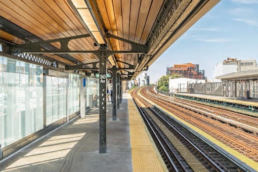 A train station platform with tracks and a yellow line on the ground.