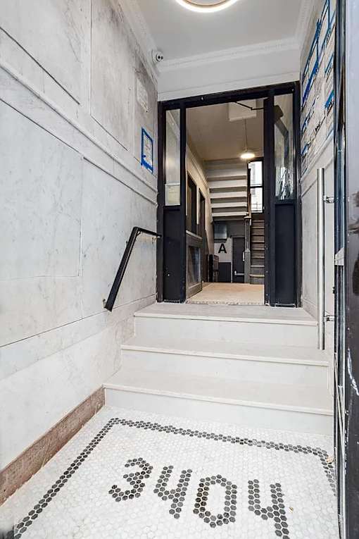 A hallway with a black and white tiled floor leading to a door with a glass window.