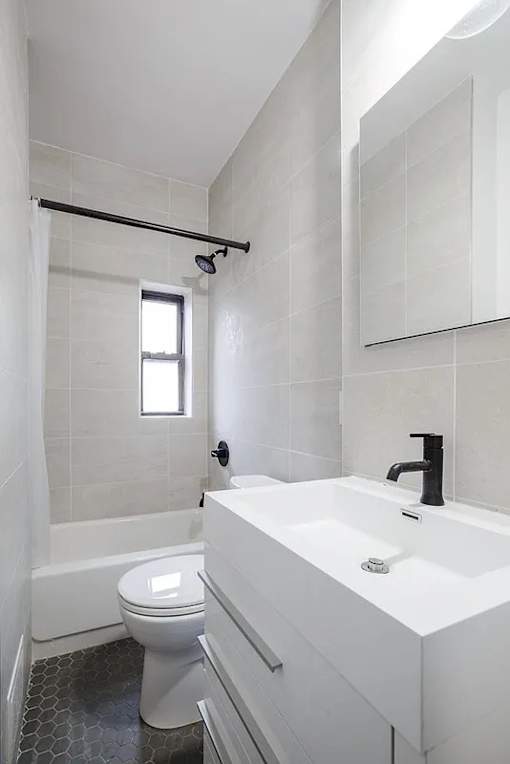 A white bathroom with a toilet, sink, and shower.