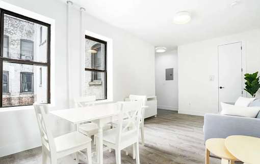 A white dining table with chairs and a couch in a room.