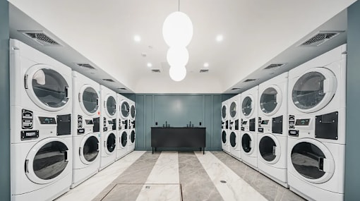 Shared laundry room with commercial washers and dryers at 260 Gold Apartments, New York
