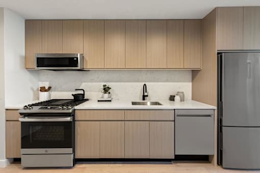 a kitchen with wooden cabinets and stainless steel appliances at The Paxton, New york