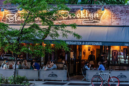 people sitting at tables outside of a restaurant at The Paxton, Brooklyn, 11201