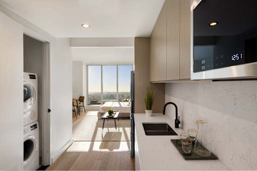 a kitchen with a sink and a dishwasher and a living room with a window at The Paxton, Brooklyn, NY 11201