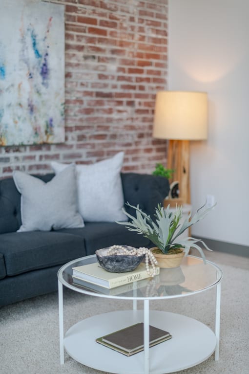 a coffee table with a book and a potted plant on top of it at The 22 Apartments, Missouri, 63103