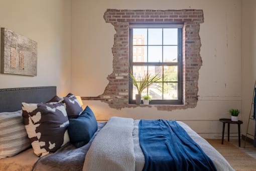 a bedroom with a exposed brick wall and a bed with a blue blanket and pillows at The 22 Apartments, Missouri