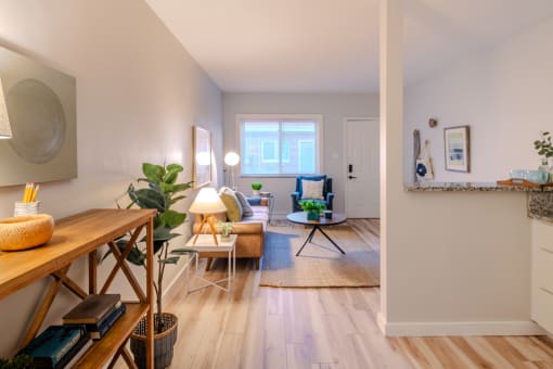 a living room with white walls and wooden floors and a dining room table