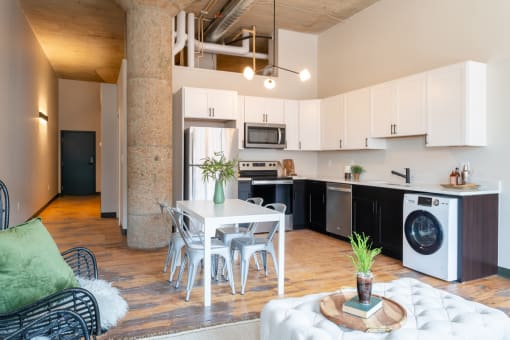 a living room with a white table and chairs and a kitchen with black and white appliances at The Draper, Missouri