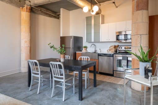 a dining area with a table and chairs and a kitchen in the background