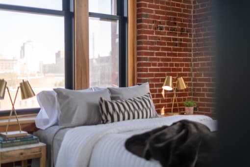 a bedroom with a brick wall and large windows
