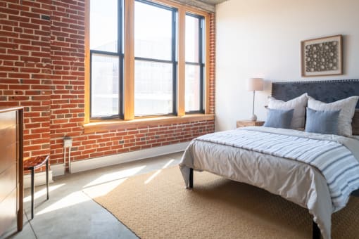 a bedroom with a bed and a brick wall