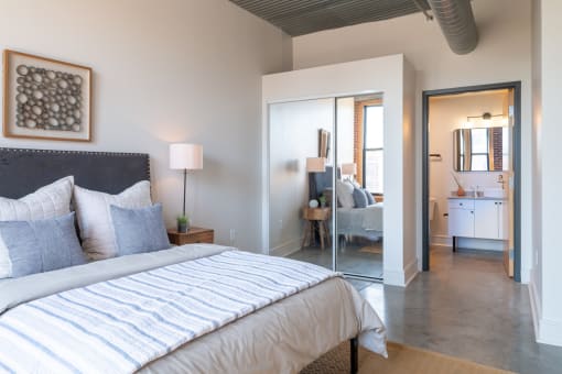 a bedroom with a large bed and a bathroom in the background