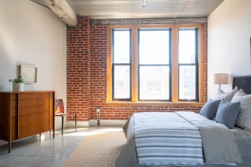 a bedroom with a bed and a dresser in front of a window