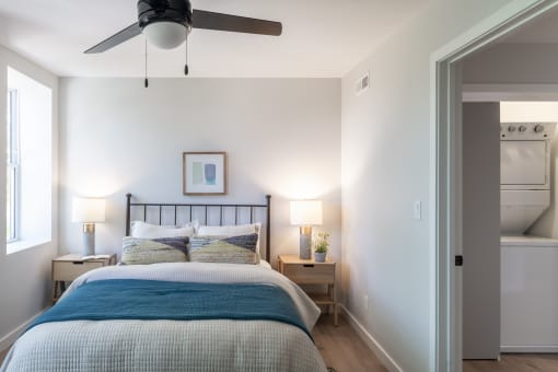a small bedroom with a bed and a light on the wall