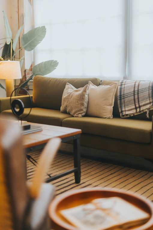 A living room with a couch, a table, and a lamp.