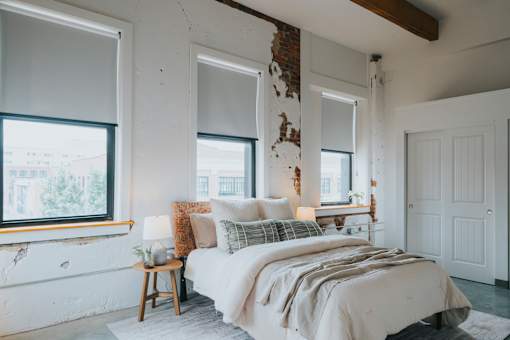 A bedroom with a bed, pillows, and a lamp.