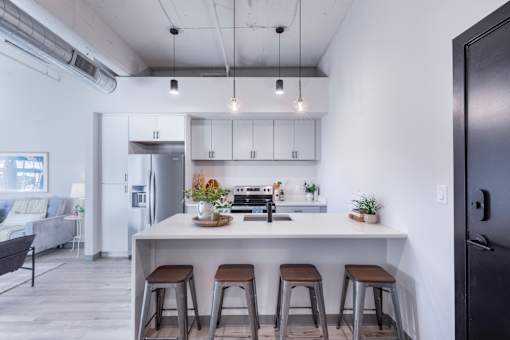 A modern kitchen with a white island and bar stools.
