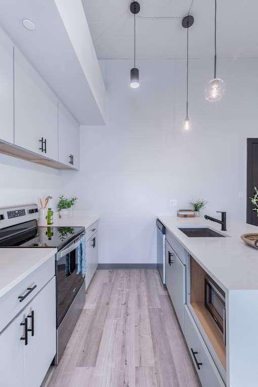 A modern kitchen with white cabinets and a wooden floor.