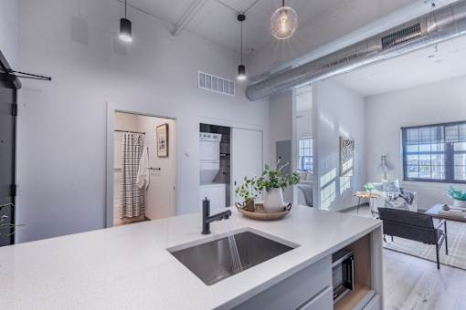 A modern kitchen with a white countertop and a stainless steel sink.