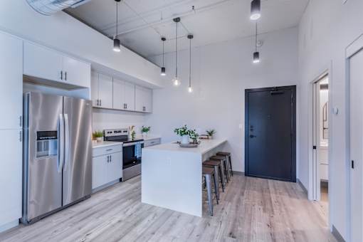 A modern kitchen with a refrigerator, stove, and bar stools.