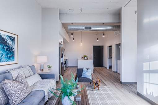 A living room with a grey couch and a painting on the wall.