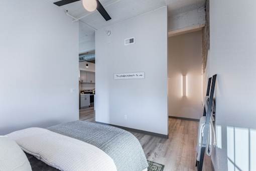 A white bedroom with a bed and a ceiling fan.