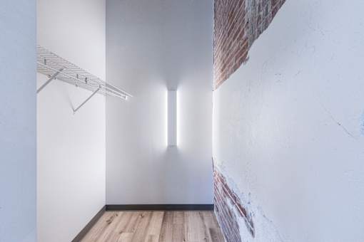 A white room with a wooden floor and a white wall with a brick accent.