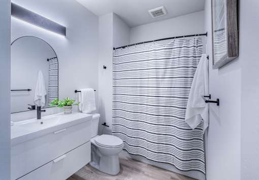 A white bathroom with a toilet, sink, and shower curtain.