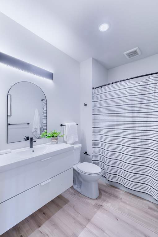 A white bathroom with a toilet, sink, and a shower curtain.