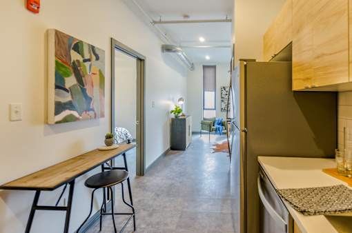 A kitchen with a refrigerator, a table and chairs, and a painting on the wall.