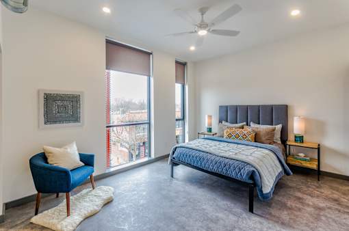 A bedroom with a blue chair and a bed with a blue comforter.
