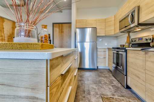 A modern kitchen with a stainless steel refrigerator and wooden cabinets.