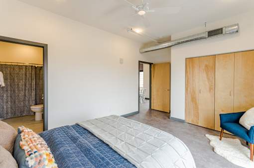 A bedroom with a bed, a chair, and a wardrobe.