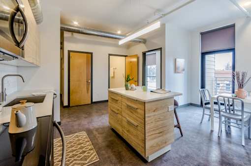 A kitchen with a wooden island and a dining table with chairs.