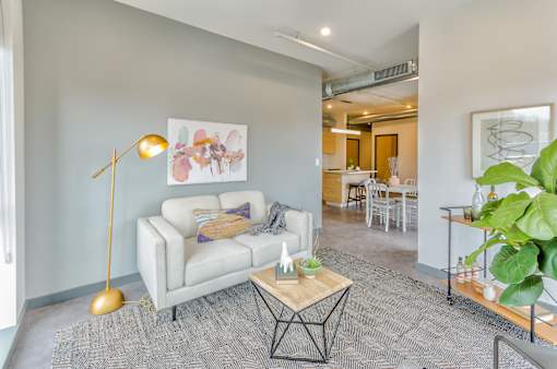 A living room with a white couch and a gold floor lamp.