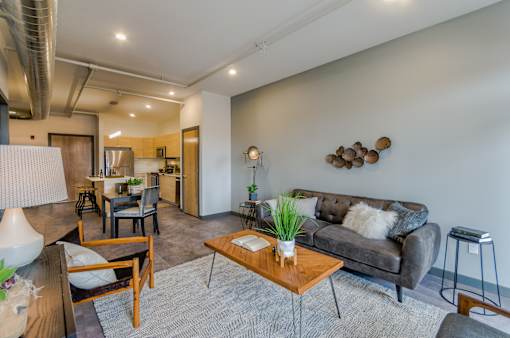 A living room with a grey couch, a wooden coffee table, and a lamp.