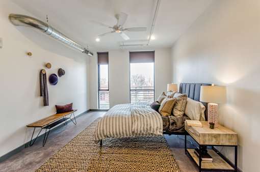 A bedroom with a bed, a bench, and a ceiling fan.