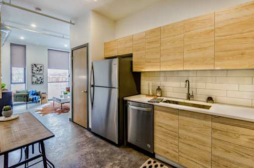 A kitchen with a refrigerator, sink, and wooden cabinets.
