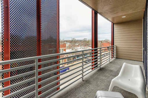 A balcony with a white chair and a metal railing.