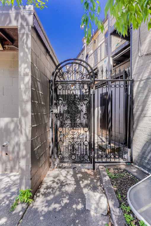 A black wrought iron gate is closed and locked.