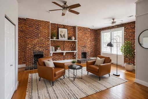 A living room with a brick wall and two chairs.