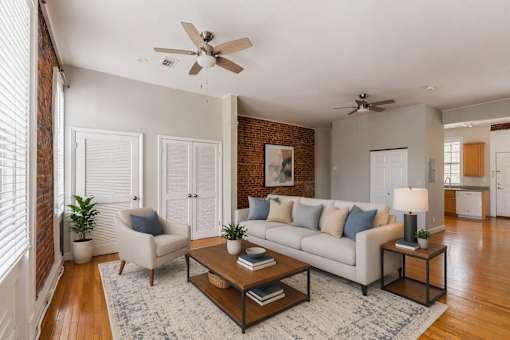 A living room with a white couch, a coffee table, and a ceiling fan.